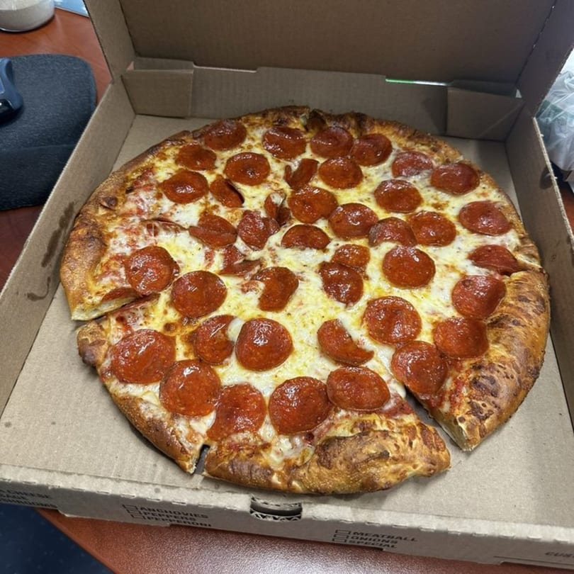 A whole pepperoni pizza from Gezziny's Homemade Pizza in a cardboard delivery box.
